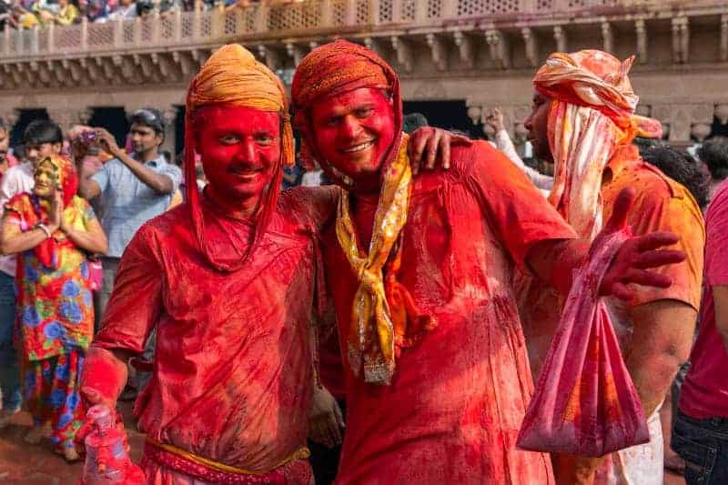 two men covered in red powder at India's holy colour festival