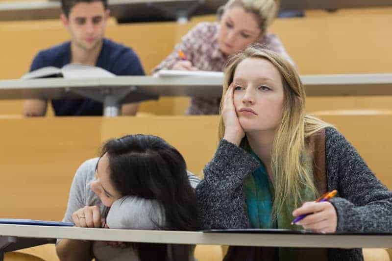 demotivated students slumping at their desk in a university lecture hall
