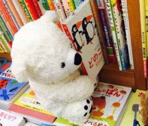 a teddy bear taking a book from a shelf