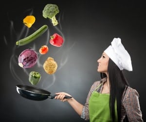 female chef tossing vegetables in frying pan