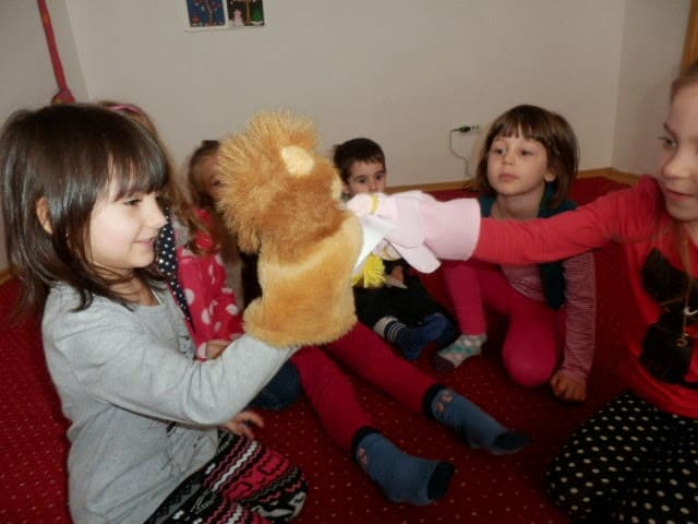Young ELLs playing with lion puppet